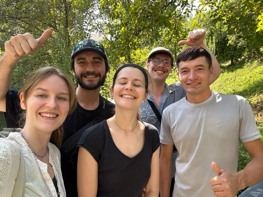 A group of smiling travelers taking a photograph together in a leafy garden