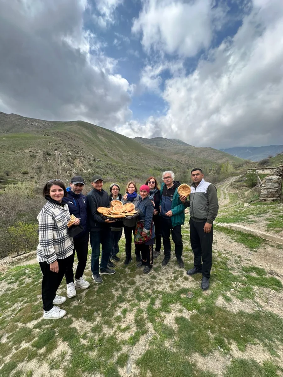 A group of hikers paused together beneath a cloudy mountain sky