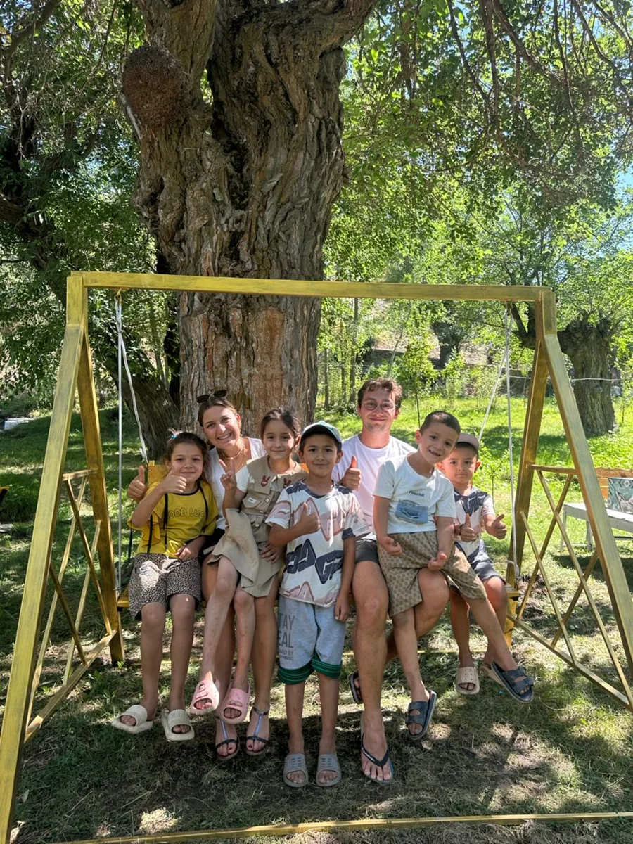 Travelers sitting together on a garden swing beneath trees