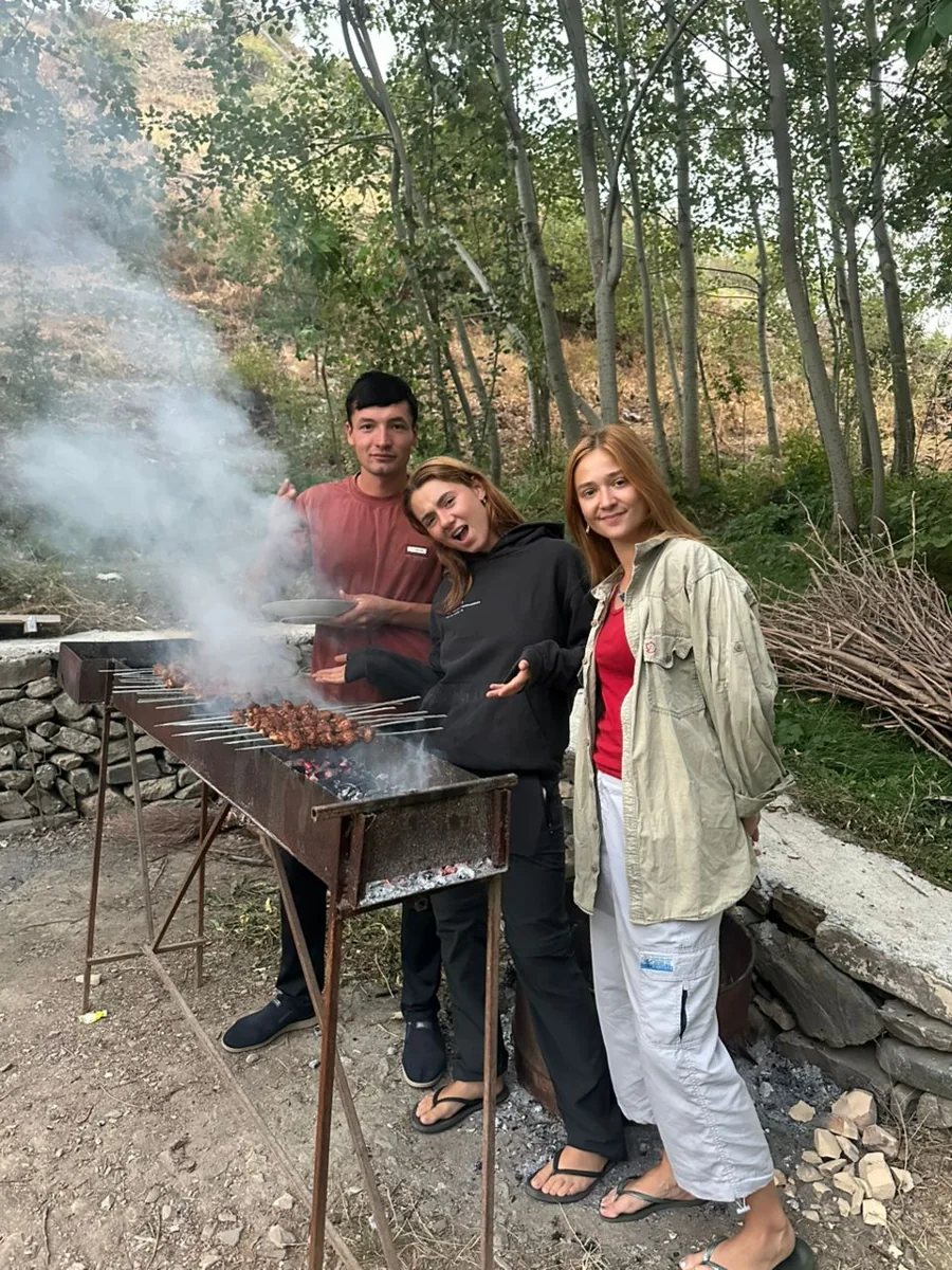 Two people preparing an outdoor meal in a tree-shaded garden