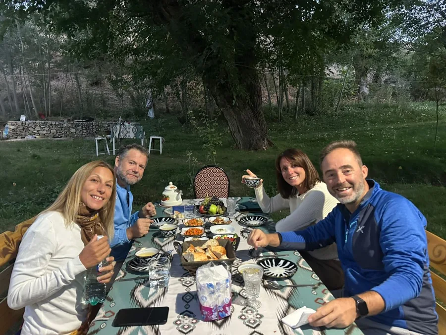 Travelers sharing a meal at an outdoor table in a shaded garden