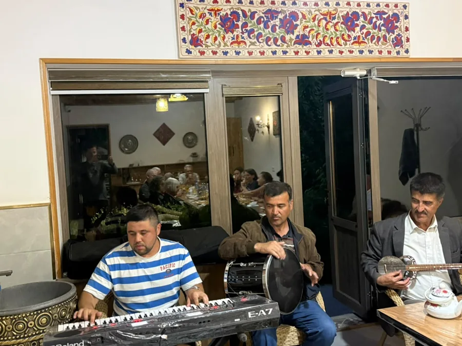 Musicians playing instruments together at a table inside a decorated room