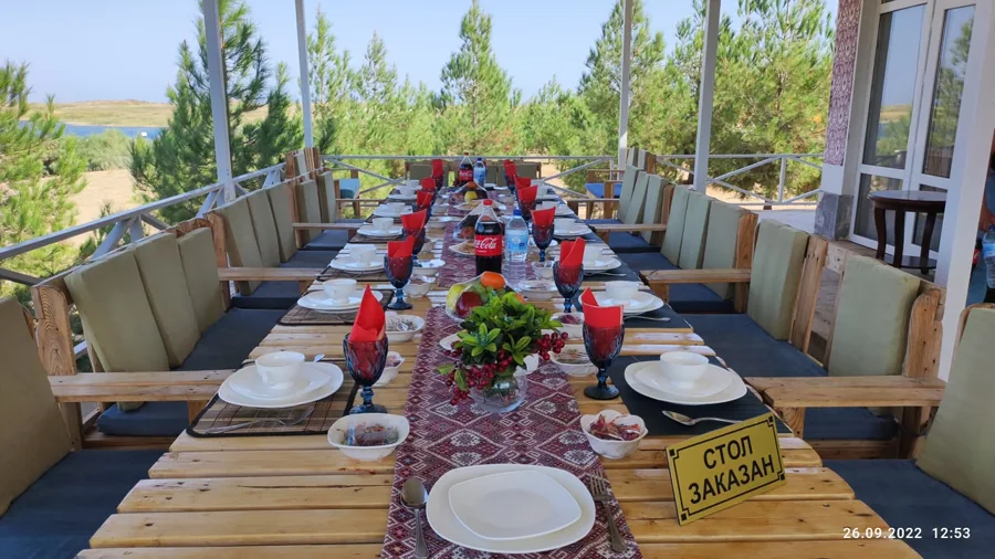 A long dining table set for guests on a shaded veranda