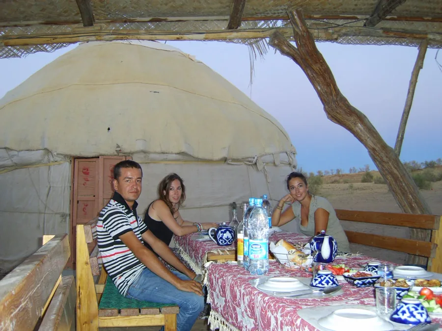 Travelers sharing a meal beside a traditional round yurt