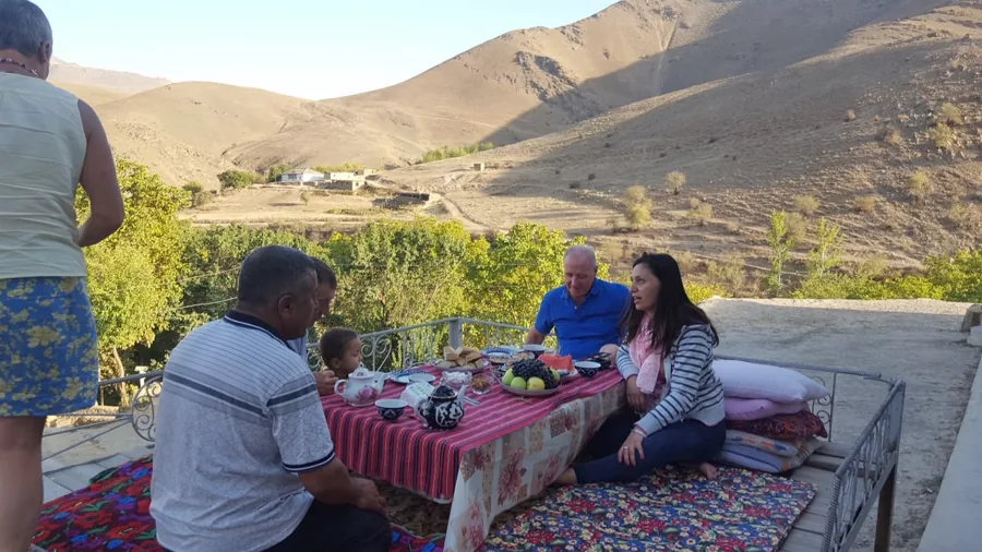 Guests sitting around a low outdoor table overlooking a mountain village