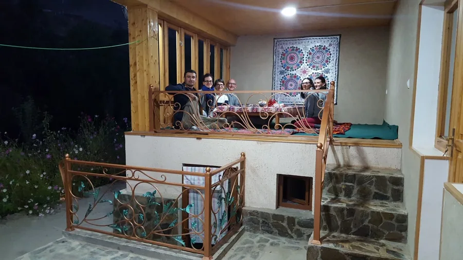 A warmly lit guesthouse veranda with people gathered around a table
