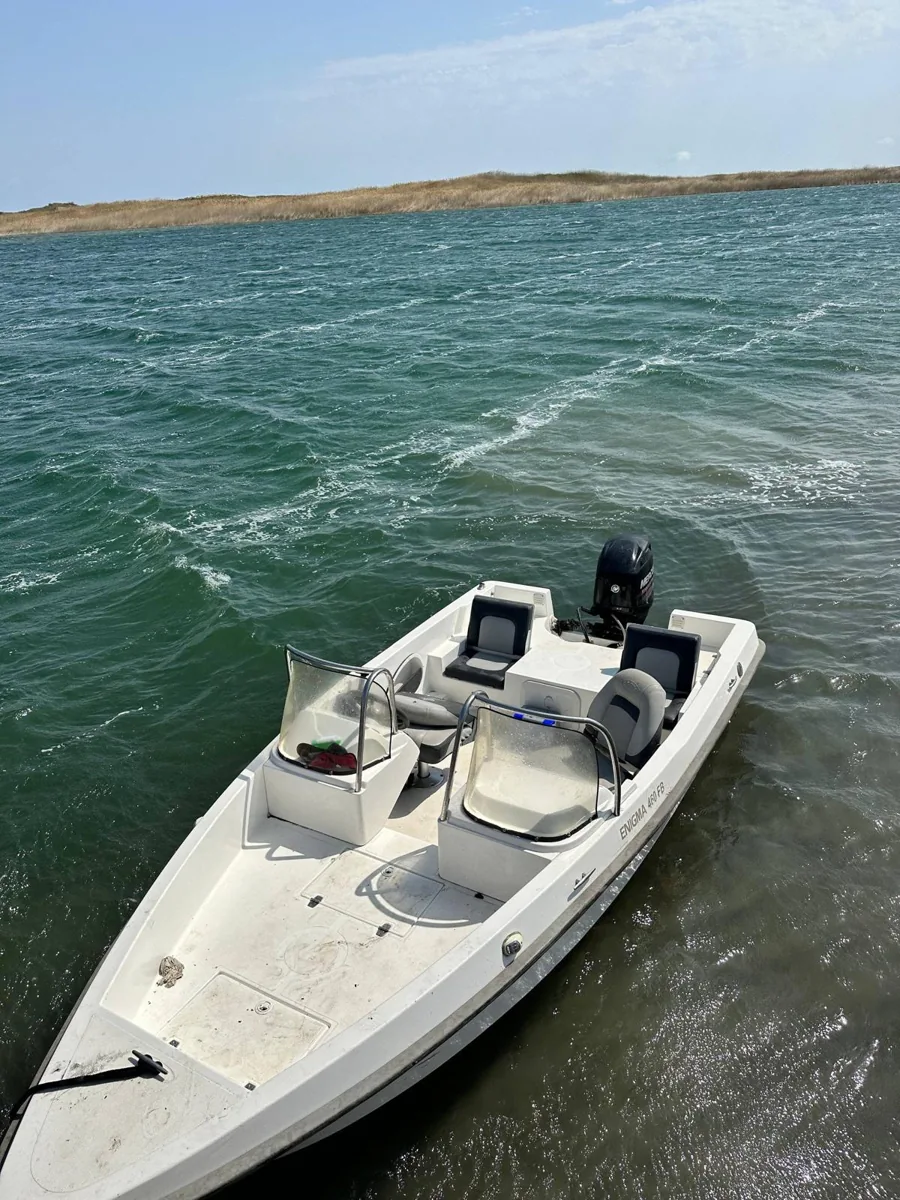 A small white boat moored beside blue-green lake water
