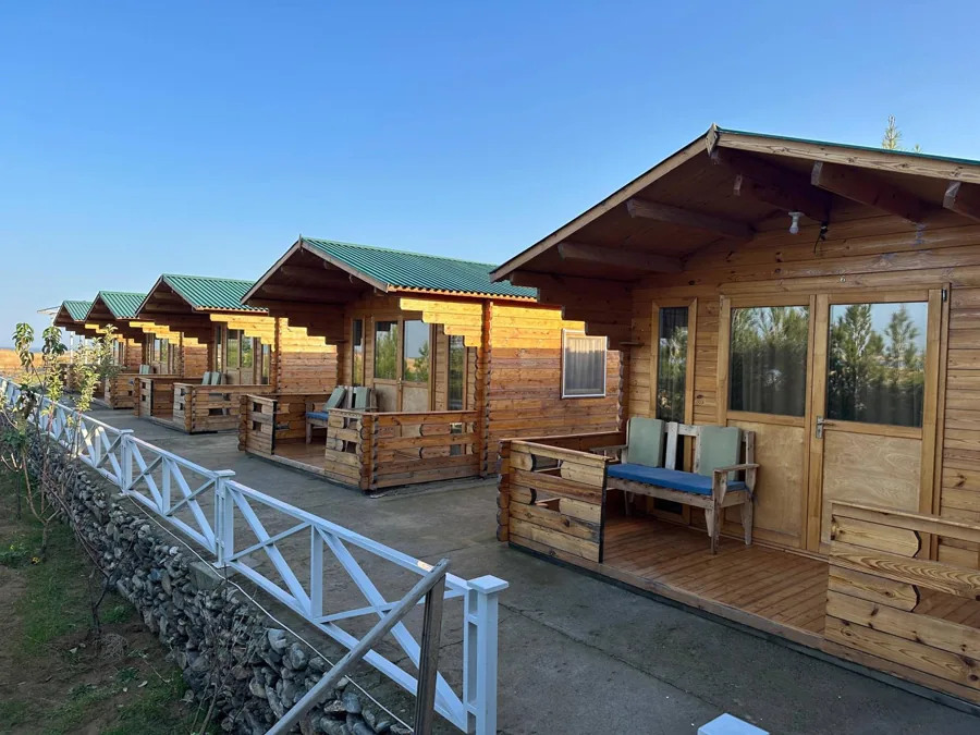 Wooden cabins beside a lake beneath a blue sky