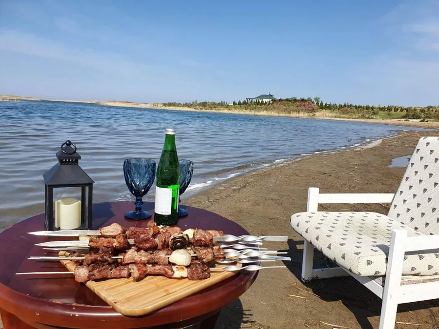 A meal served on a wooden table beside a sunlit lake