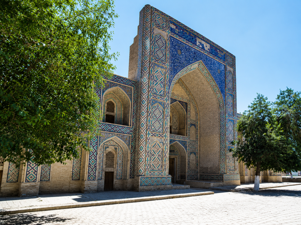 fe56831b-5587-4528-b2dc-781626caee2f - Silk Road Elite - Silk Road Elite Ornate tiled madrasa entrance framed by green trees