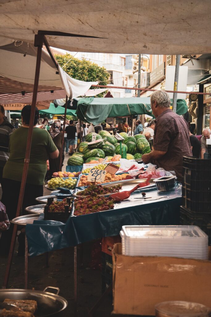 Vendor arranging fresh produce at an outdoor market stall