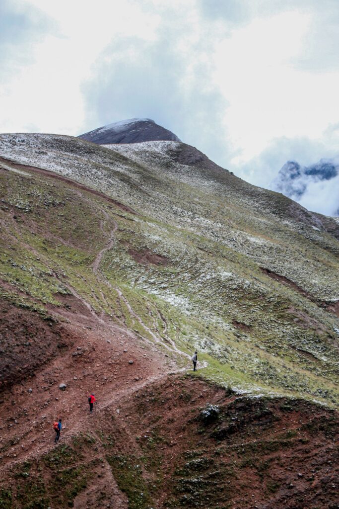 Hikers following a steep trail across a high mountain slope