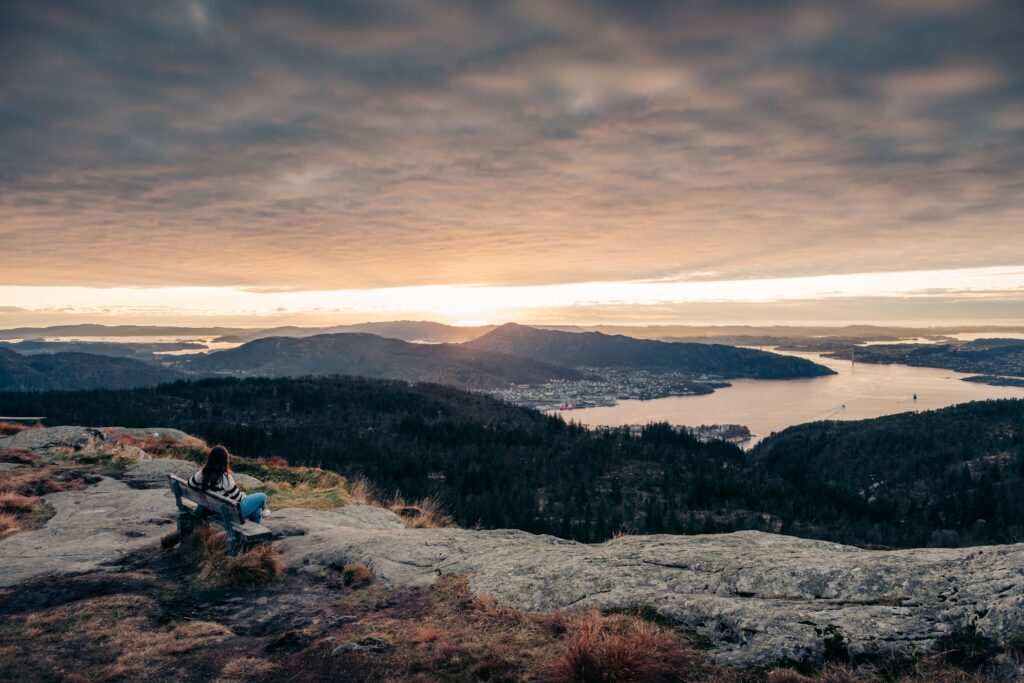 Hiker resting at a rocky viewpoint above lakes and forest