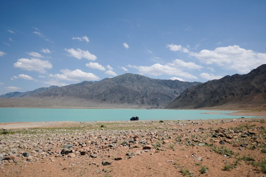 Turquoise mountain lake beside a rocky shore and ridgeline
