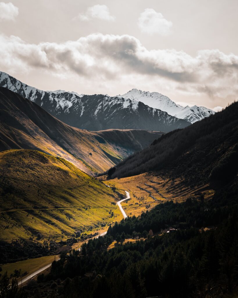 Winding road through a deep valley beneath snowcapped peaks