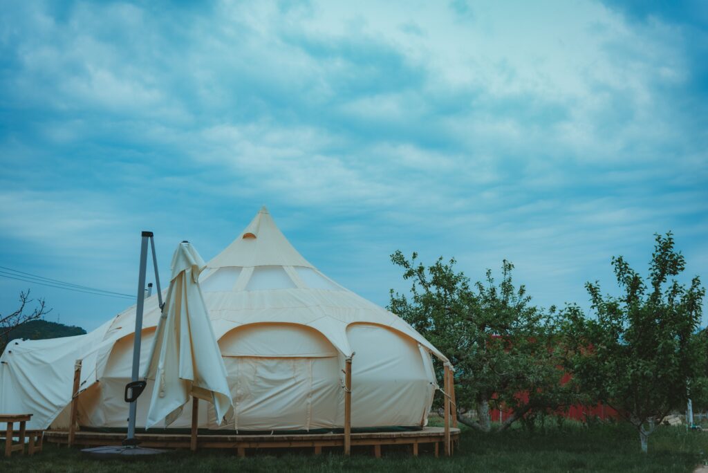 White glamping tents on wooden platforms beneath a cloudy sky