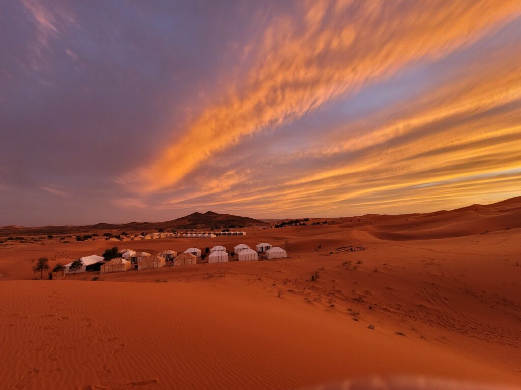 Desert yurt camp beneath a colorful sunset
