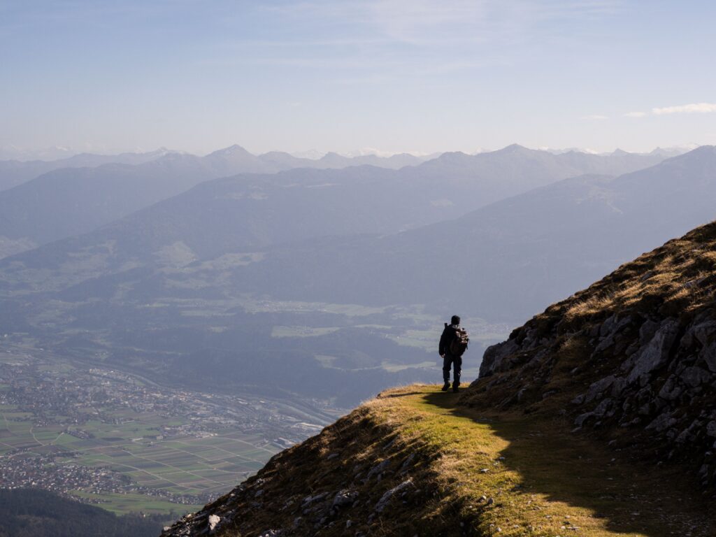 Hiker standing on a grassy ridge above a wide valley
