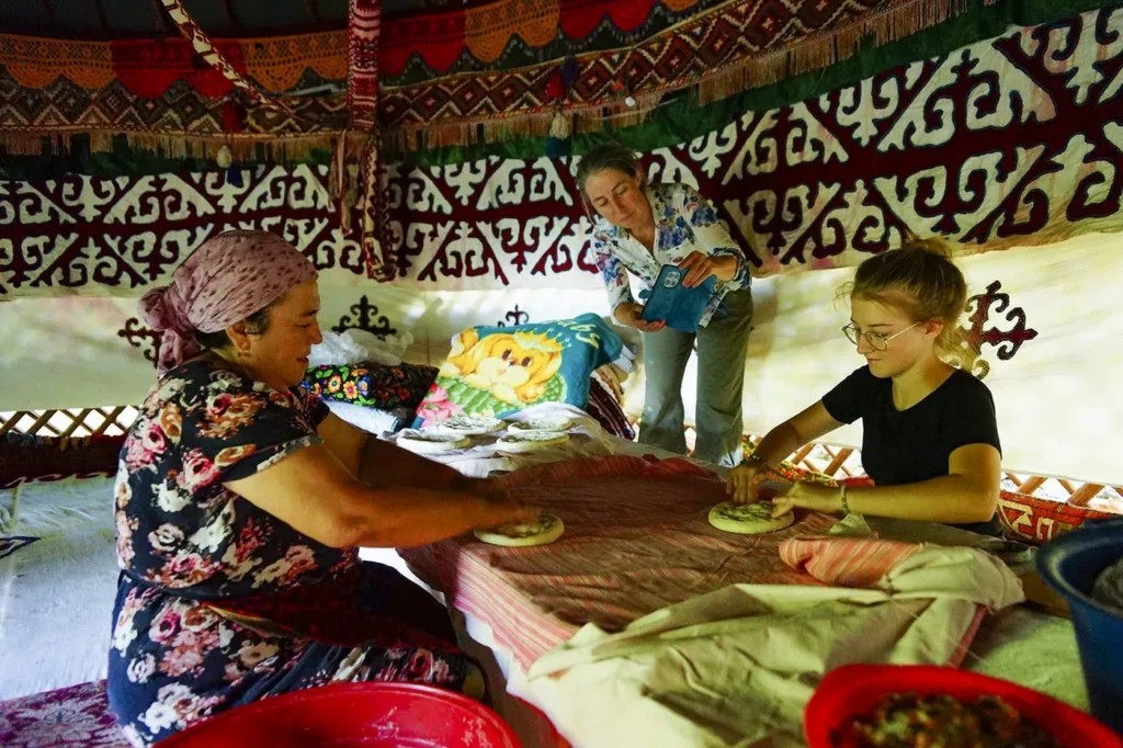 Guests learning to shape Uzbek bread with a village host inside a decorated yurt