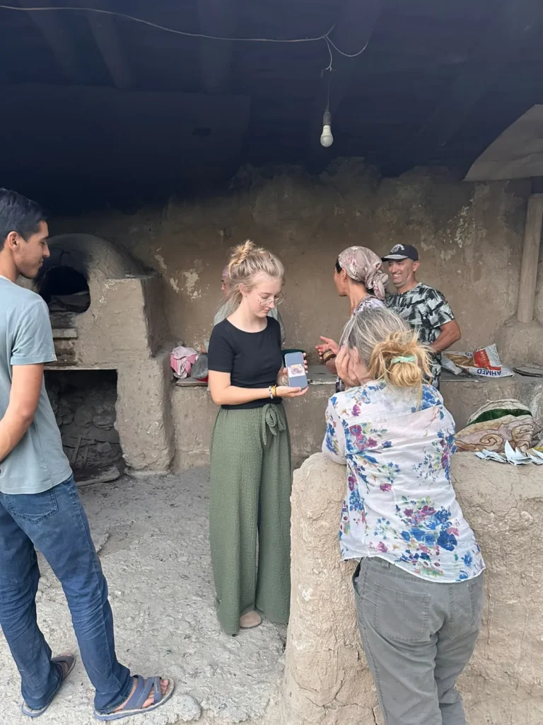 Guests talking with local residents beside a traditional clay oven