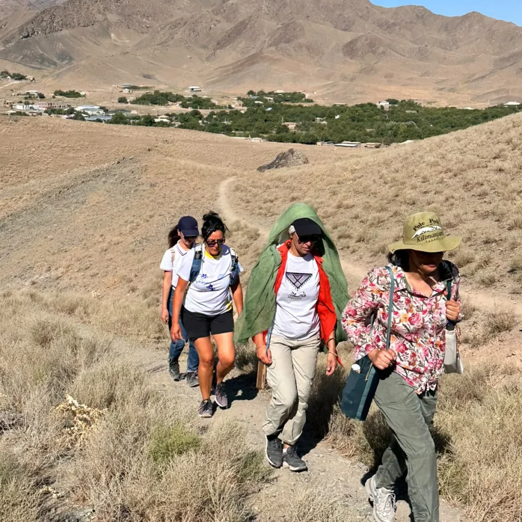 Hikers climbing a dry mountain trail above a Nuratau village