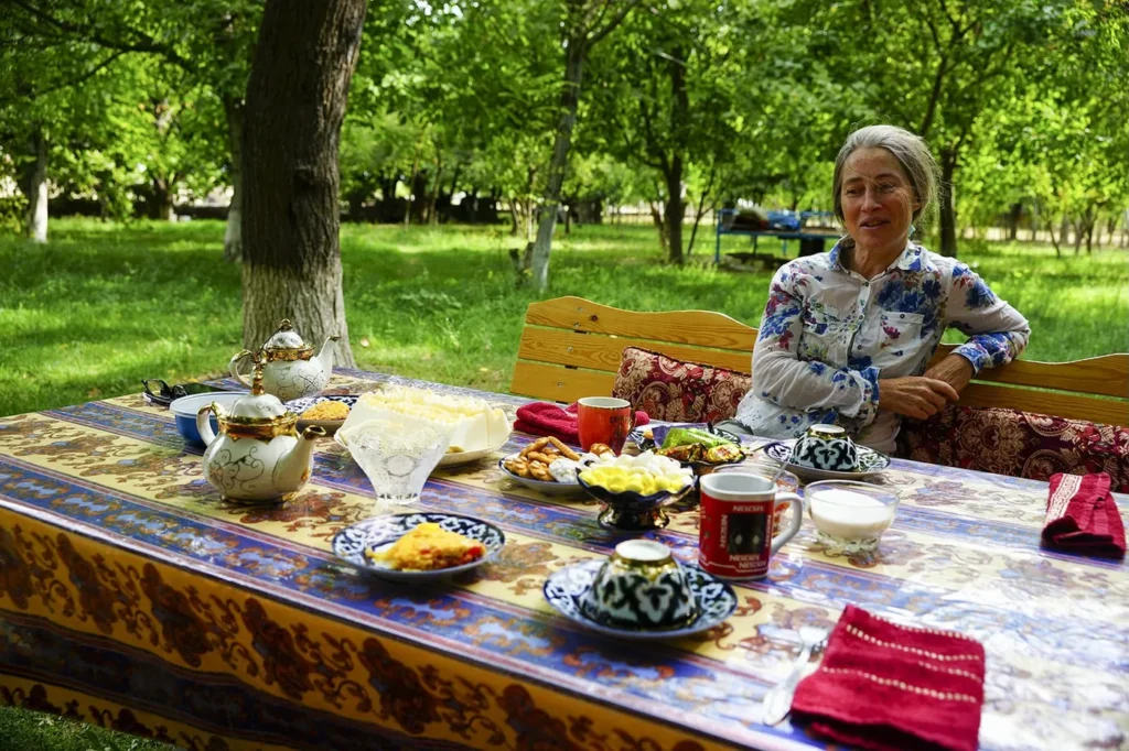Guest seated at a breakfast table in a leafy Nuratau village garden