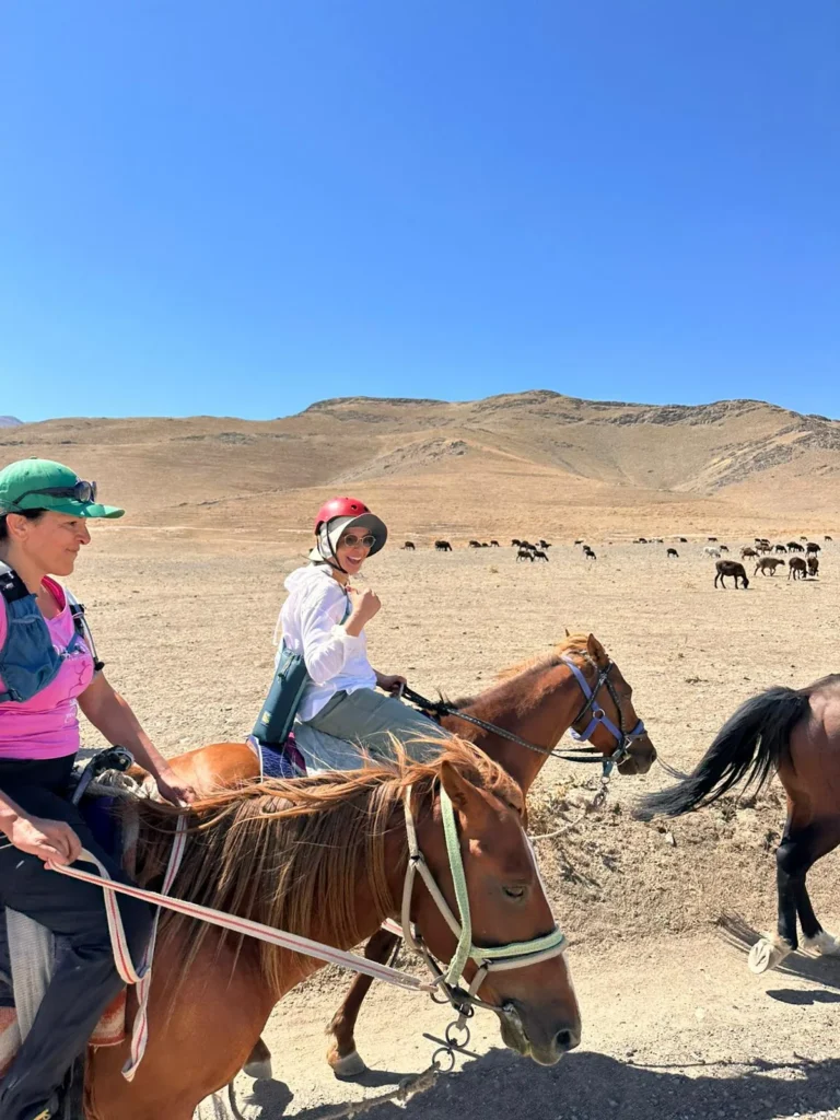 Horse riders pause beside a grazing herd on a dry Nuratau mountain plateau