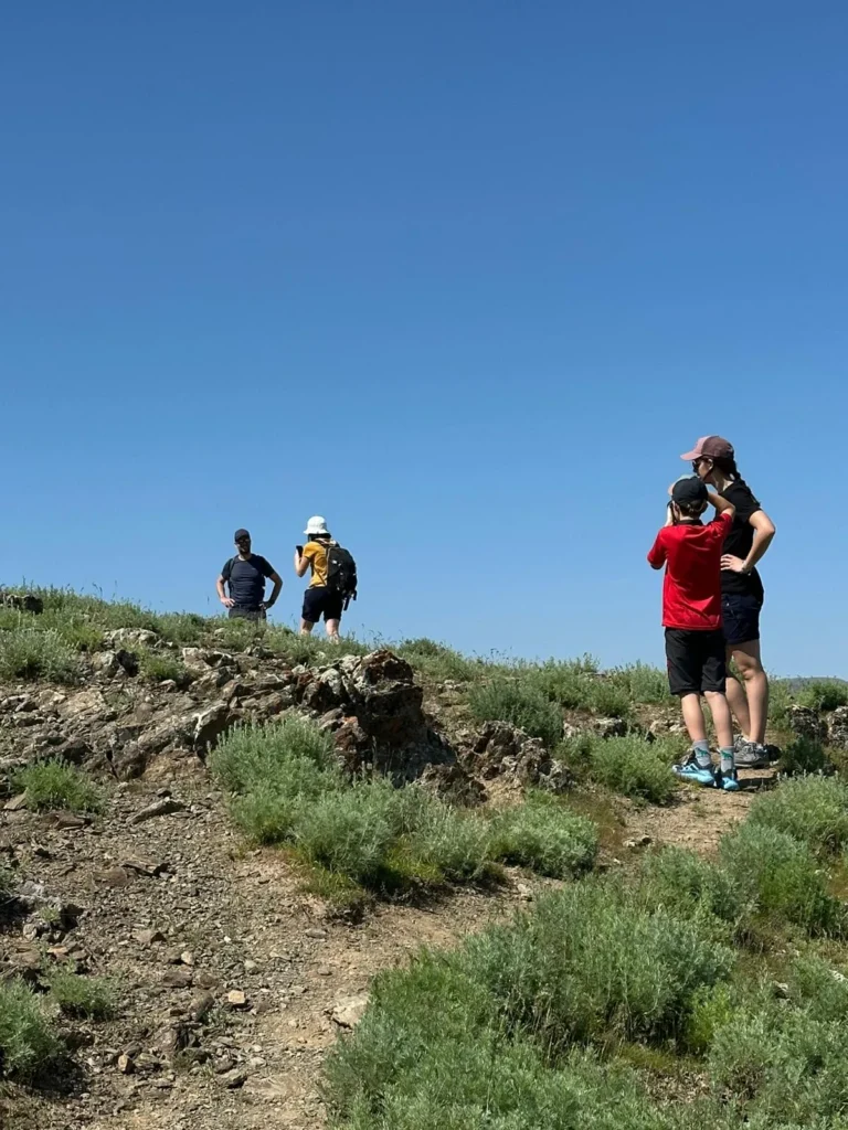 Adults and a child hiking on a rocky ridge in the Nuratau Mountains