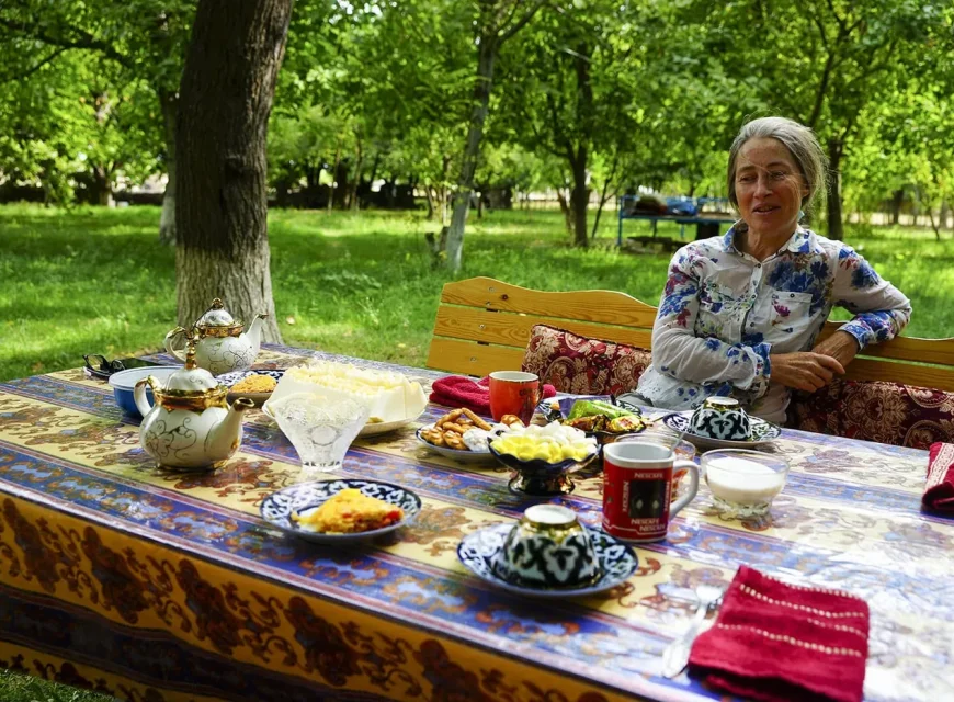 Guest seated at a breakfast table in a leafy Nuratau village garden
