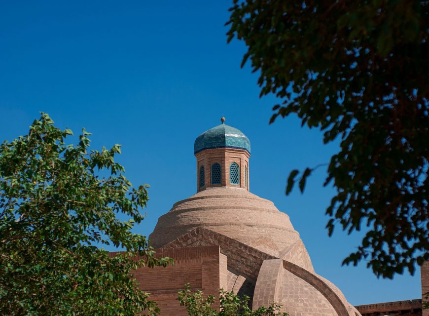 Turquoise-domed historic tower framed by tree branches