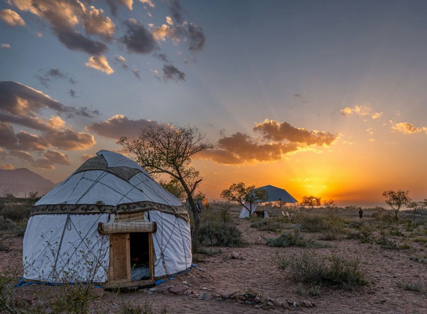 Traditional yurt camp beneath a dramatic sunset sky