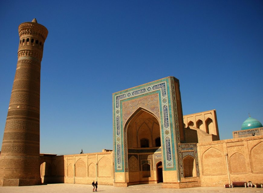 Decorative Islamic arch and minaret against a deep blue sky