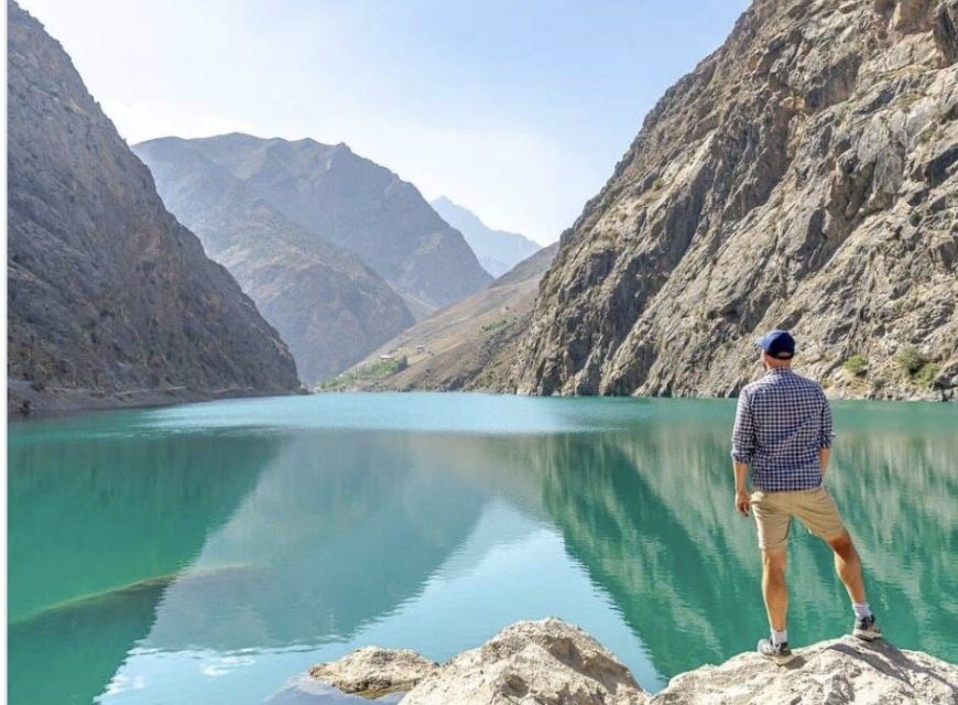 A traveler beside a turquoise lake on the Seven Lakes route in Tajikistan.